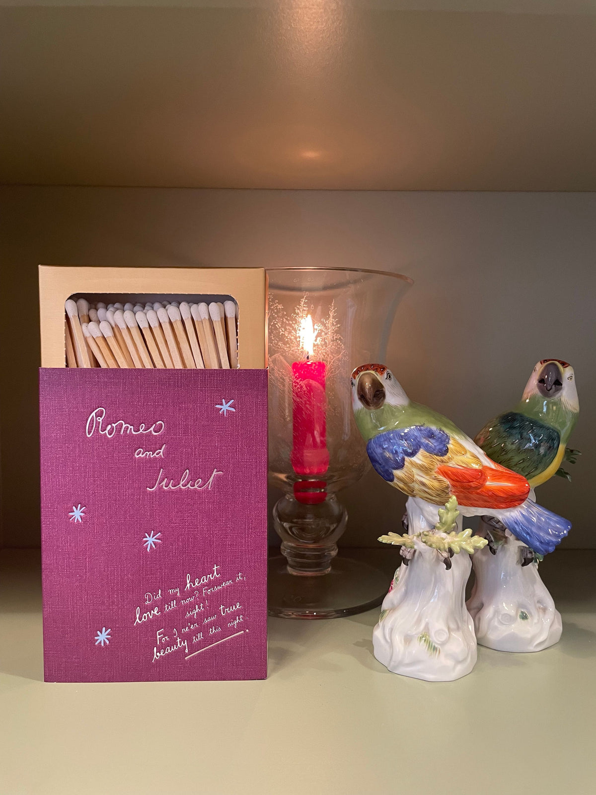 Romeo and Juliet matchbox beside a lit red candle